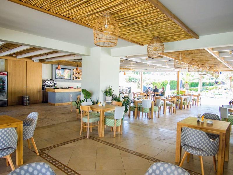 Prostorná světlá jídelna s dřevěným nábytkem a přírodním dřevěným stropem v hotelu.