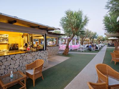 Accogliente bar all'aperto con posti a sedere e tavoli accanto a un bancone rivestito in pietra.