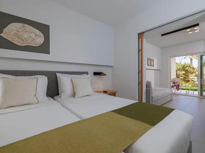 Camera d'hotel luminosa con letto matrimoniale, mobili moderni e vista su terrazza con giardino.