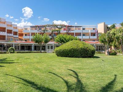 Edificio dell'hotel con più piani circondato da un grande prato verde e cespugli.