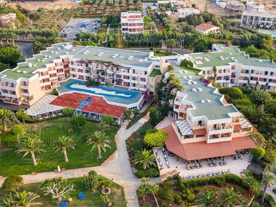 Vista aerea di un complesso alberghiero con piscina, giardini e aree verdi circostanti.