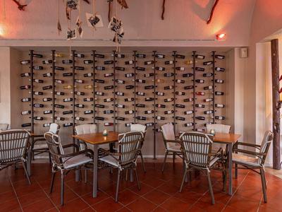 Ristorante con tavoli, sedie e una grande parete con portabottiglie di vino.