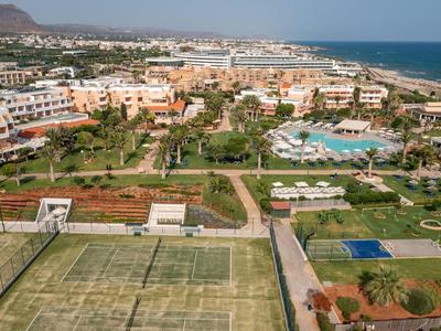 Veduta di un resort con campi da tennis, piscine e vista sul mare sullo sfondo.