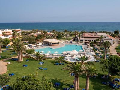 Vista di una piscina dell'hotel con lettini e palme vicino al mare