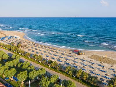 Vista de una playa de arena con muchas sombrillas y tumbonas junto al mar.