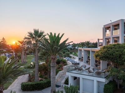 Complejo hotelero con palmeras y terraza al atardecer.