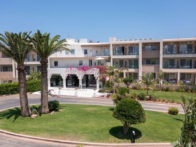 Edificio de hotel moderno con palmeras y césped verde bien cuidado.