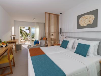 Habitación de hotel moderna con cama doble, escritorio y balcón con vista al mar.