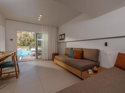 Habitación de hotel moderna con sofá, escritorio y vista abierta a una piscina al aire libre.
