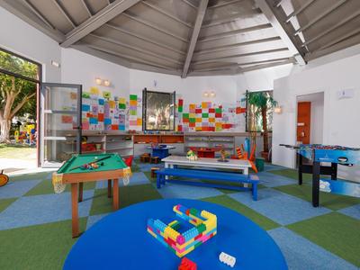 Sala de recreo luminosa con juegos de mesa, mesa de billar y futbolín en un hotel.