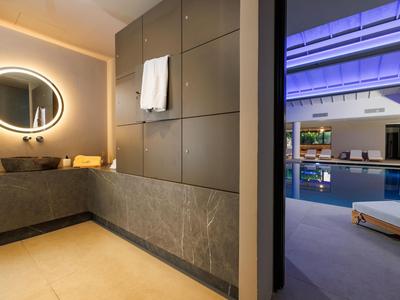 Baño elegante con espejo redondo iluminado y vista a la zona de la piscina del hotel.