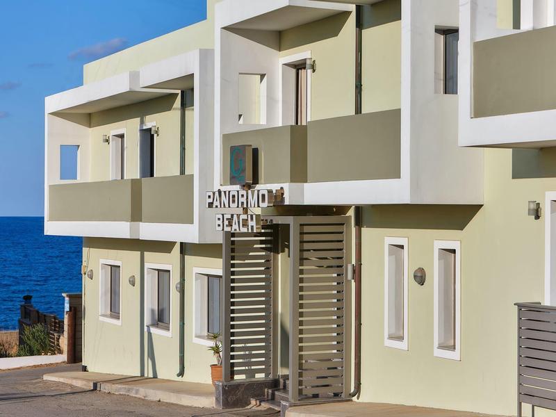 Bâtiment d'hôtel moderne avec balcons et vue sur la mer sous un ciel bleu clair.