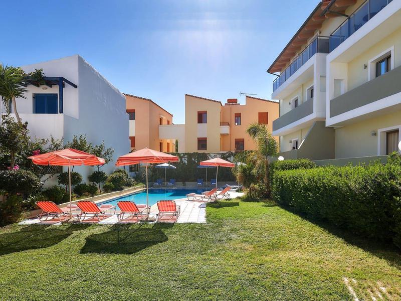 Jardin d'hôtel avec chaises longues, parasols et architecture moderne sous un ciel bleu.