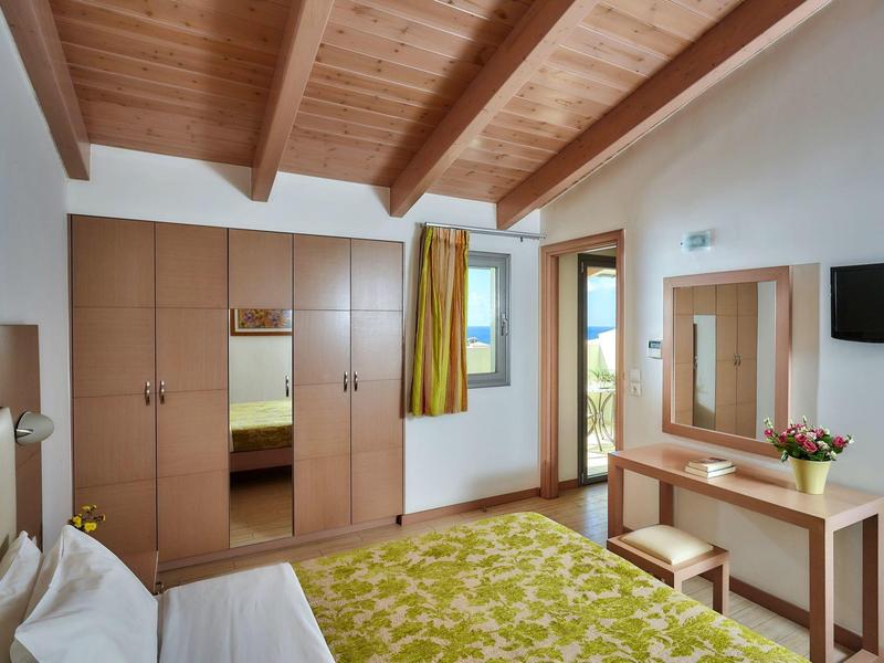 Chambre lumineuse avec plafond en bois, grand placard, tapis vert et bureau avec miroir.