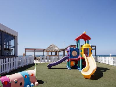 Children's playground with slide on a green rooftop area, sea and blue sky in the background