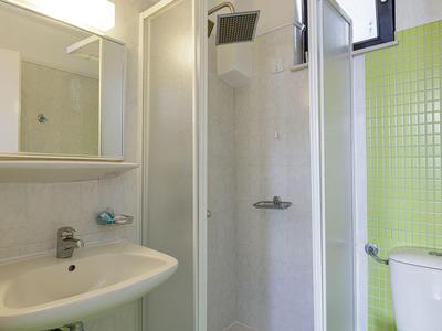 Modernes Badezimmer mit Duschkabine, Waschbecken und grünen Wandfliesen.