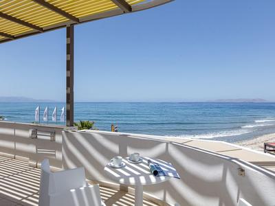 Balcony with chairs and table overlooking the sea under clear sky.