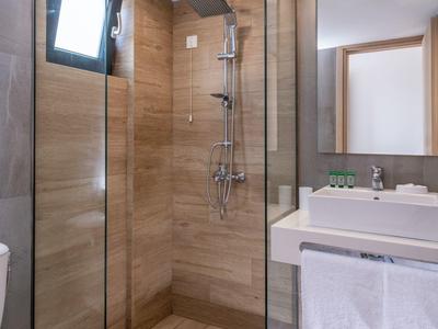 Modern bathroom with glass shower enclosure, wood accents, and vanity with mirror.