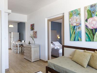 Bright room with sofa, dresser, dining table, and bedroom in the background.