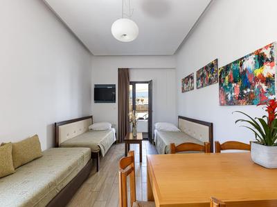Living room with two sofas, dining table, colorful paintings, and access to a balcony.