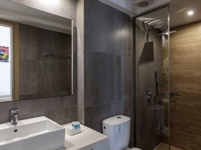 Modern bathroom with sink, toilet, mirror, and walk-in shower with brown tiles.