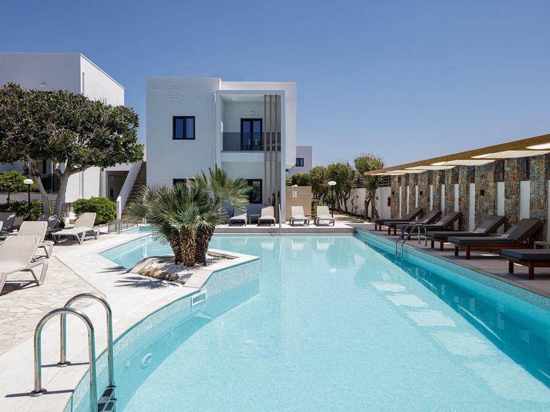 Modern hotel pool with lounge chairs and white building under clear blue sky