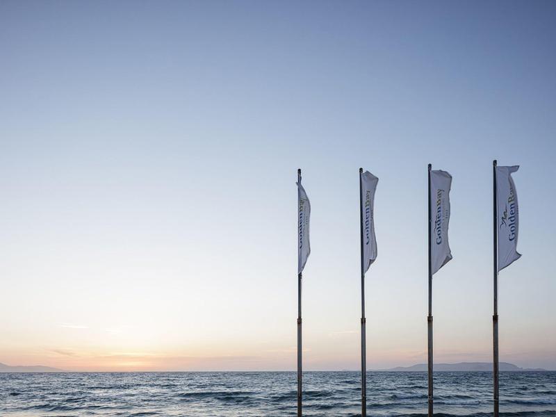 View of sea and horizon at sunset with four waving white flags.