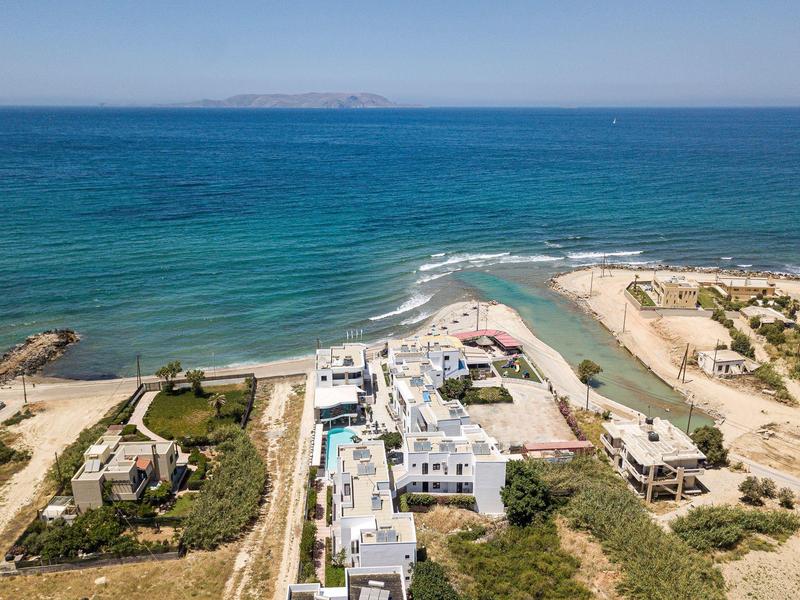 Aerial view of a coastal hotel with blue sea and sandy beach.
