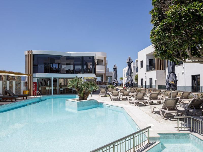 Modern outdoor pool area with lounge chairs and surrounding buildings under clear sky.