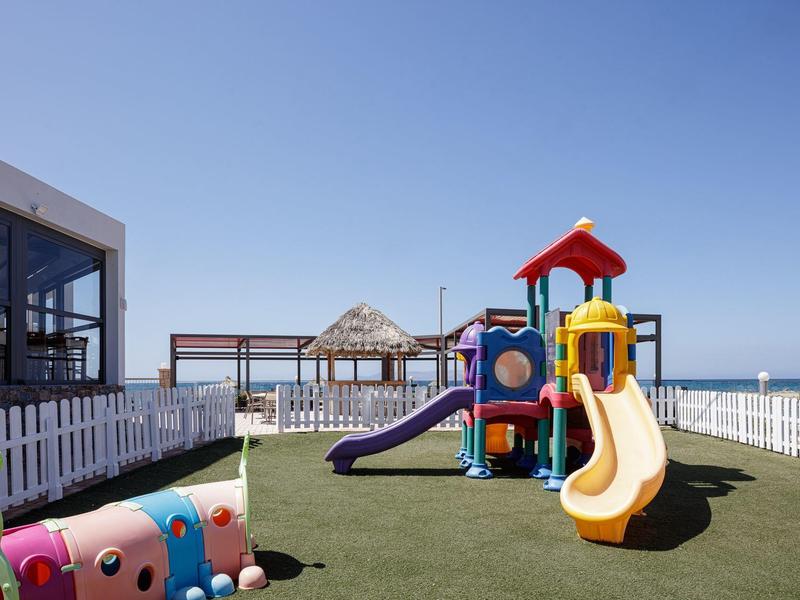 Children's playground with slide on a green rooftop area, sea and blue sky in the background