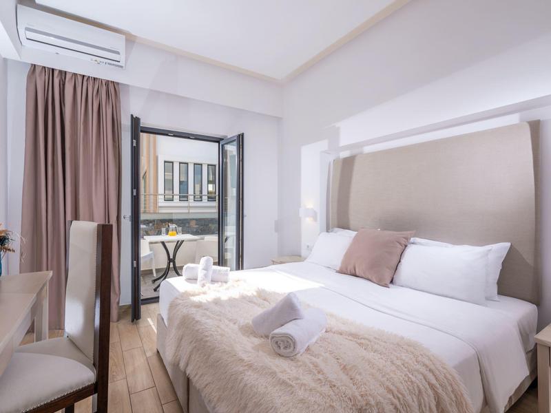 Bright hotel room with double bed, balcony, and modern decor.