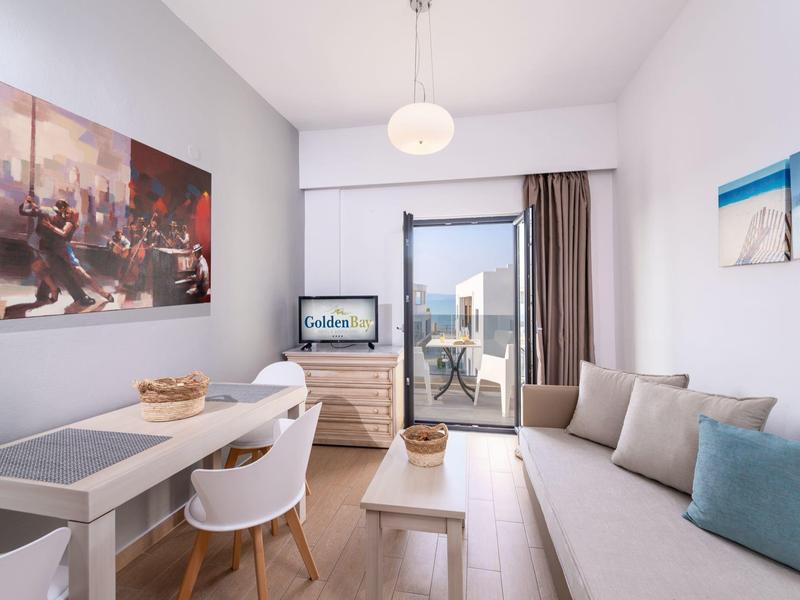 Modern living area with sofa, dining table, and sea view through balcony door.