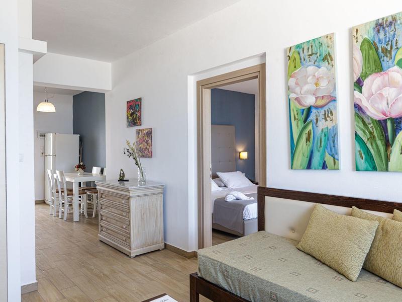 Bright room with sofa, dresser, dining table, and bedroom in the background.