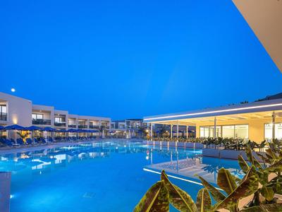 Nowoczesny hotelowy basen o zmierzchu z jasnym niebieskim oświetleniem i otaczającymi leżakami.