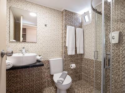 Compact bathroom with shower, toilet, sink, and towels on the wall.