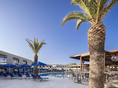 Beach hotel with palm trees, sun umbrellas, and lounge area under clear blue sky.