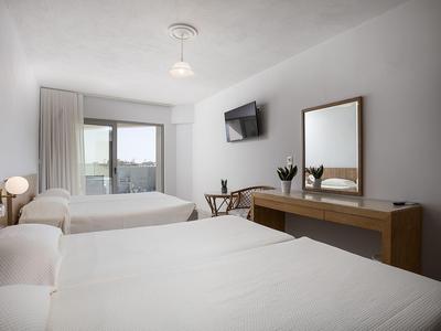 Bright hotel room with two beds, large mirror, and wall-mounted TV.