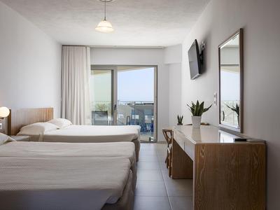 Modern hotel room with two single beds, balcony, and desk with mirror.