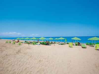 Una spiaggia sabbiosa tranquilla con sedie a sdraio verdi e ombrelloni vicino al mare blu.