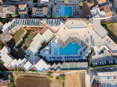 Luftaufnahme eines großen Hotels mit mehreren Schwimmbecken, Sonnenterrassen und umliegenden Gebäuden.
