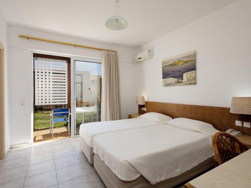 Světelý hotelový pokoj se dvěma jednolůžky, balkonem a výhledem na zahradu.