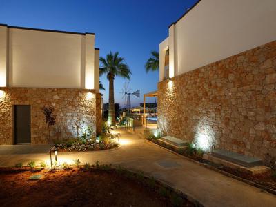 Sentiero illuminato tra due edifici con palme la sera in un resort alberghiero.