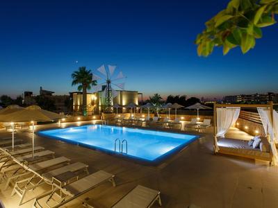 Oświetlony basen z leżakami i przytulną cabaną o zmierzchu.