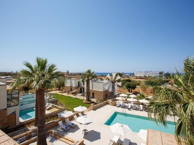 Nowoczesny obiekt z basenem, palmami i widokiem na morze pod czystym niebem.