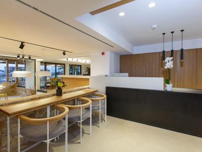 Nowoczesna recepcja z ladą, stołkami barowymi i jasną, przyjazną atmosferą.