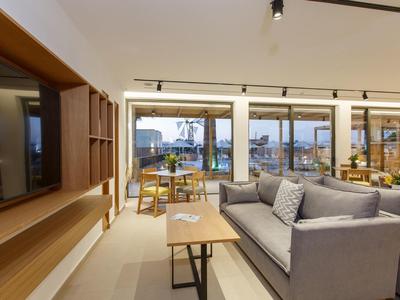 Nowoczesny salon z szarą sofą i dużymi oknami z widokiem na miasto i port