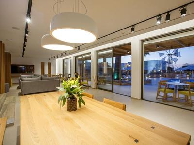 Nowoczesna jadalnia z dużym drewnianym stołem, kwiatami i widokiem na taras i basen.