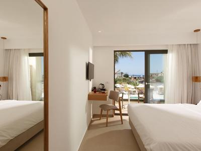 Nowoczesny pokój hotelowy z dużym łóżkiem, biurkiem i widokiem na słoneczny taras.