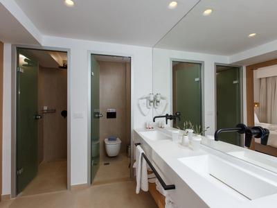 Nowoczesna łazienka z podwójną umywalką, dwoma prysznicami i otwartym widokiem na sypialnię