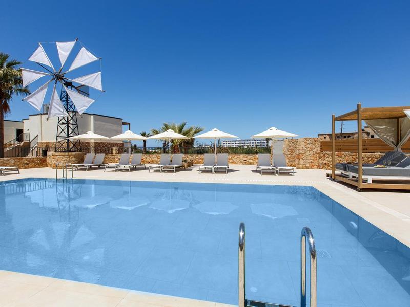 Nowoczesny basen z leżakami, parasolami, wiatrakiem i czystym błękitnym niebem.